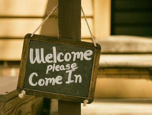 Quelle: unsplash.com / Aaron Burden, https://unsplash.com/de/fotos/willkommensbeschilderung-auf-focus-photography-AvqpdLRjABs Kreidetafel mit der Aufschrift: Welcome please come in
